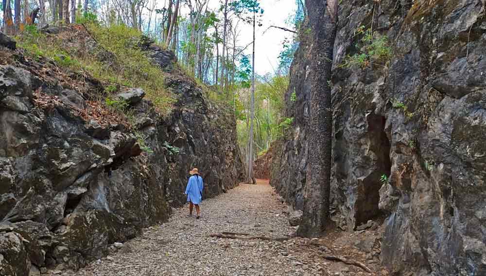 A woman in a blue dress walking by in Hellfire Pass, Thailand-Burma Railway during World War II
