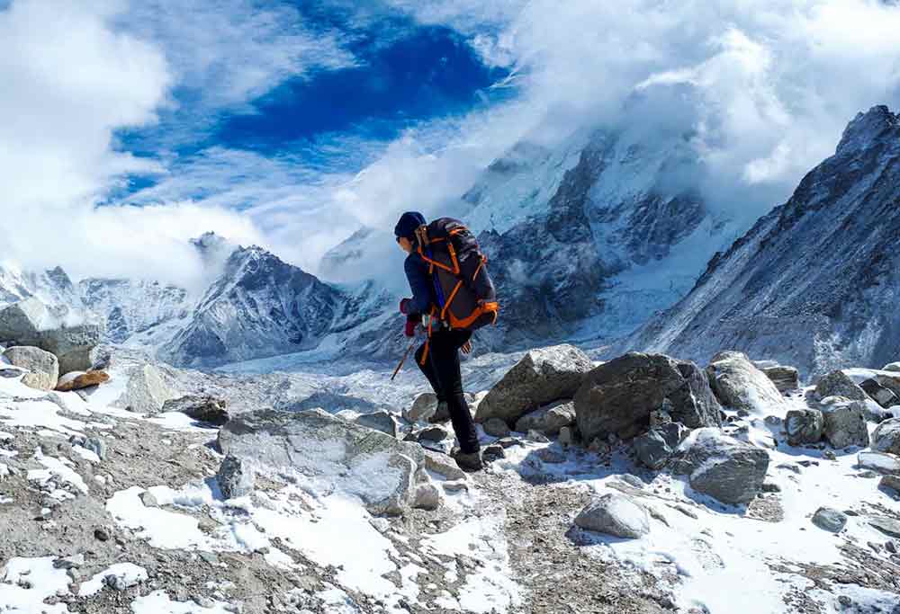 A man hike at Everest Base Camp in Nepal with large rock covered with snow