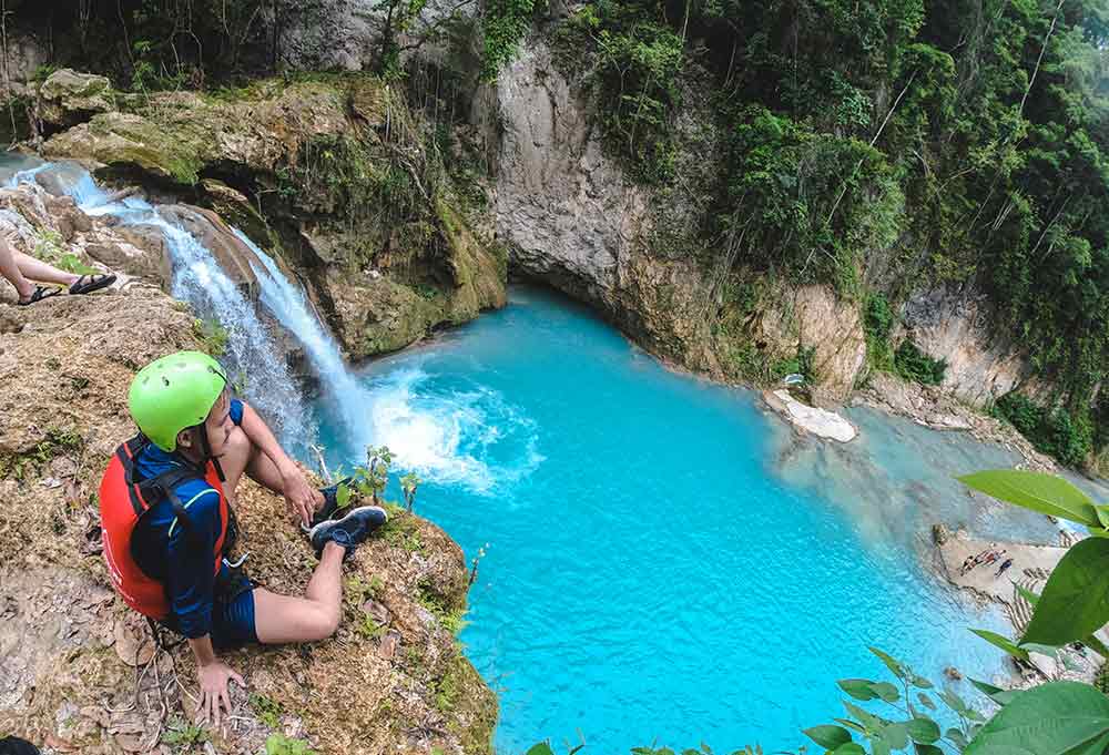Kawasan Falls in Cebu, Philippines featuring a multi-layered waterfall with its turquoise waters surrounded by a high cliff mountains