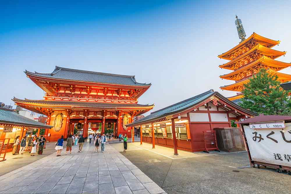 Senso-ji, a Buddhist temple in Japan featuring a red two-tiered roof and five story red and gold pagoda on the side