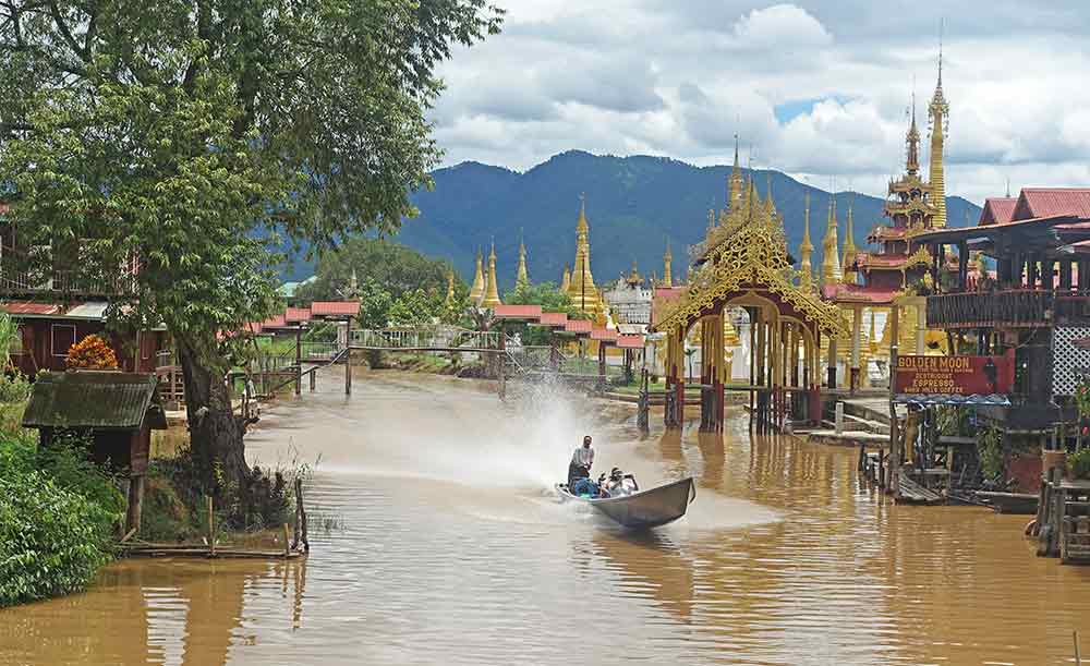 Inle Lake in Myanmar features red-gold attractions at the side, while boats roam at the center of the lake.