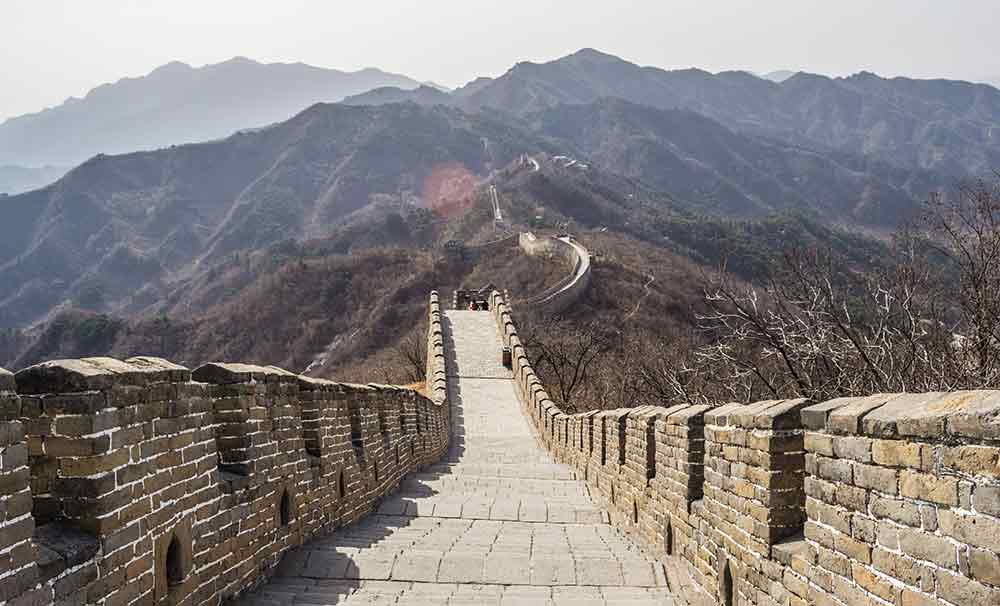 The Great wall of China featuring the longest wall in the world made of stone brick surrounded by mountains