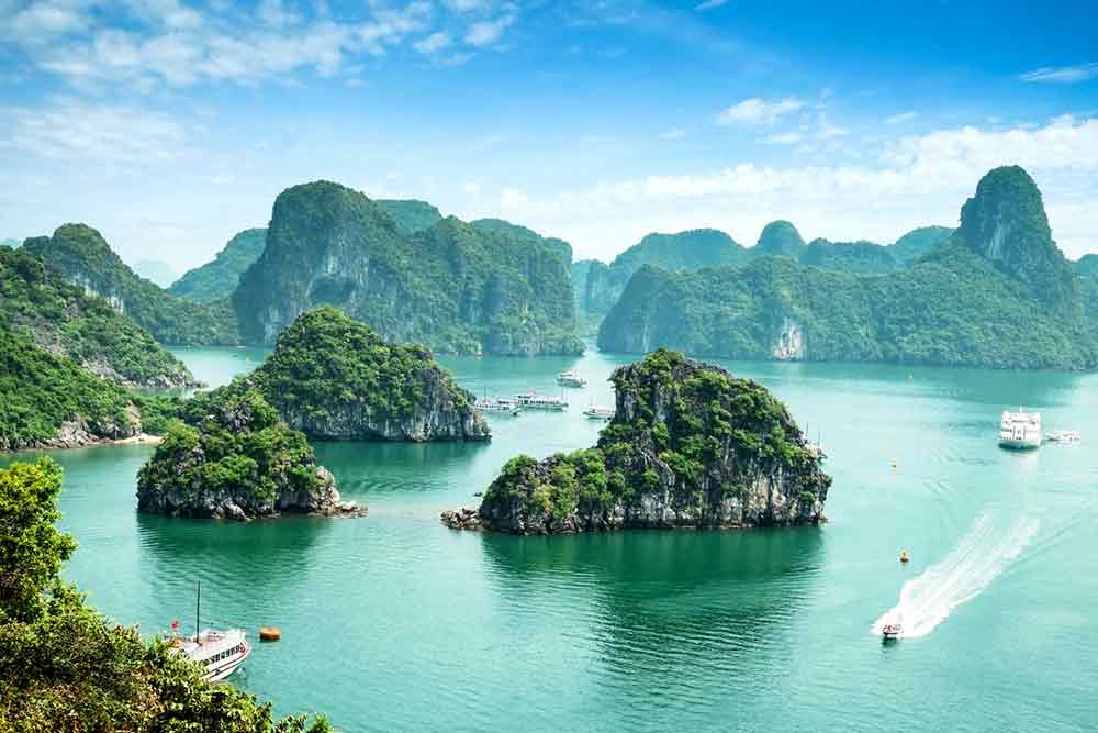 Halong Bay in Vietnam featuring numerous high cliff mountain islands surrounded by water and boats
