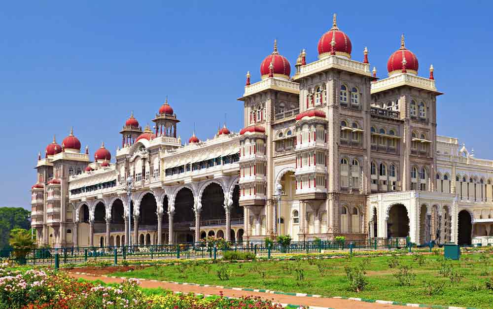Mysore Palace in India is a magnificent fortress with a red dome at the top, and it showcases multiple arches and windows with intricate details.