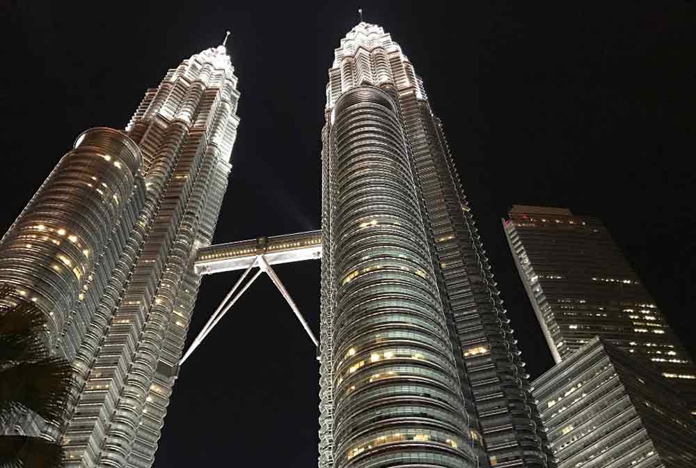 The Petronas Twin Towers, featuring the tallest twin towers in the world, are beautifully illuminated during the night.