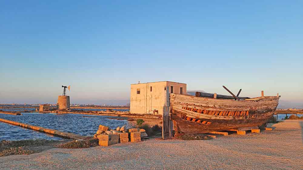 An old boat in the forground at the salt flats at sunset.