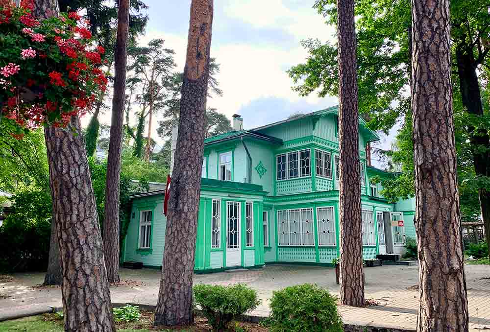 Best Of The Baltics: 23 Unmissable Things To Do In The Baltics 13 A green villa in Jurmala is surrounded by tall trees and plants on a sunny day.