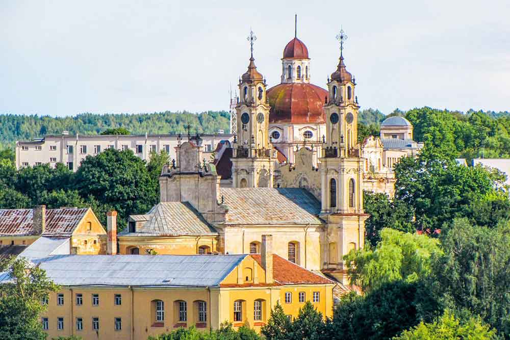 Best Of The Baltics: 23 Unmissable Things To Do In The Baltics 1 A tall red-roofed church and vibrant houses surrounded by trees in Kaunas, Lithuania