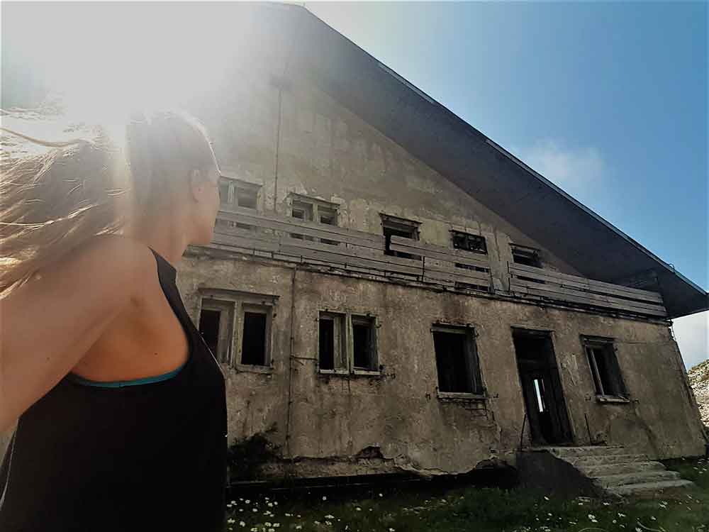 A woman in a black sleeveless shirt took a picture on the abandoned barracks at the top of the Pljesevica Mountain hike