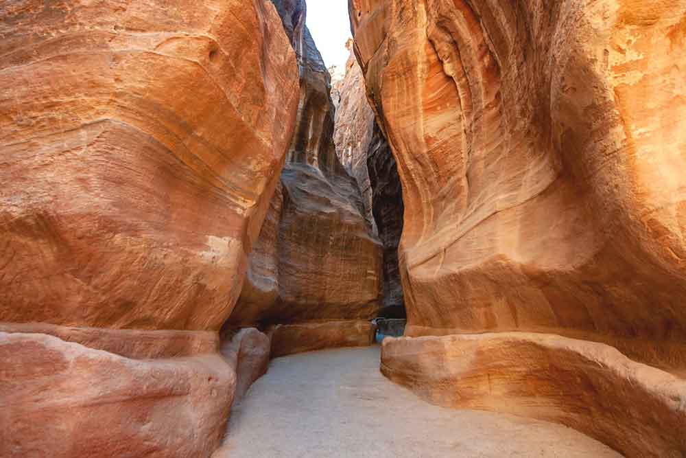 High towering cliff walls in Petra with passage at the middle