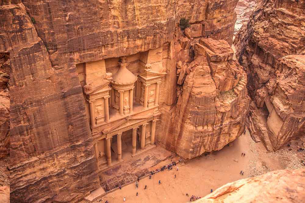 The Treasury in Petra showcases its sandstone structure, with columns and intricate carvings, set within a rock formation