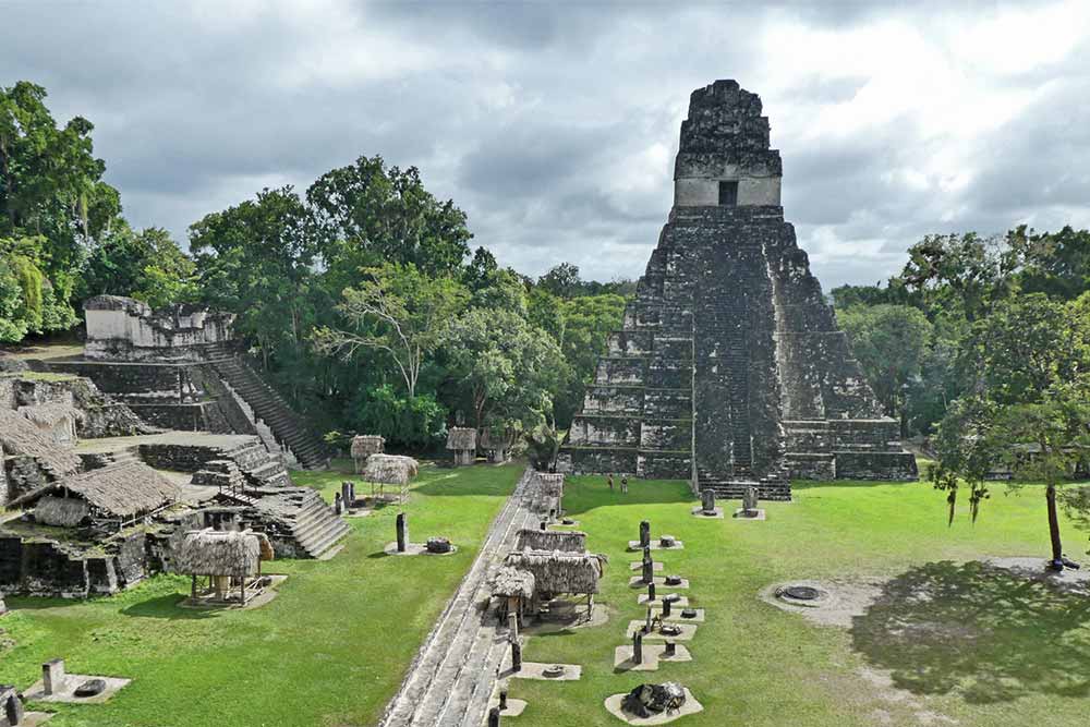 The quintessential Tikal features a gray-black pyramid temple with steep stone steps leading to the top
