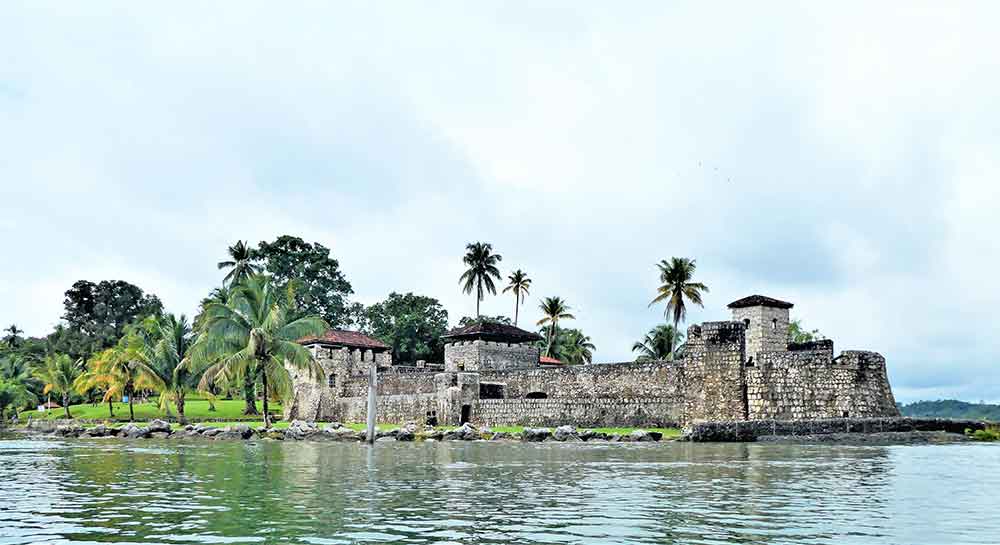 Castillo de San Felipe de Lara features a thick stone walls and structures surrounded by lake and trees