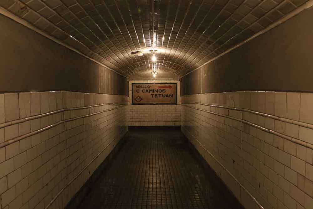 Estación Museo Chamberí features a light-creepy hallway with a sign of Direccion C Caminos Tetuan at the middle