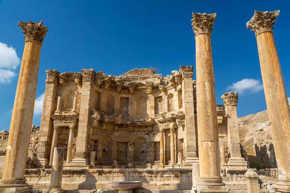 Jerash Ruins feature sandstone bricks standing with columns against a clear blue sky