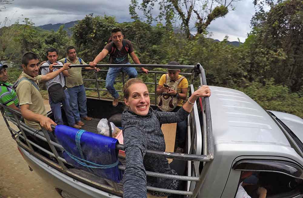 A woman taking a selfie with friends at the back of 4x4 cattle truck