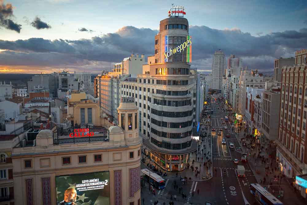The iconic Schweppes Building stands in the middle of the busy streets, surrounded by buildings.