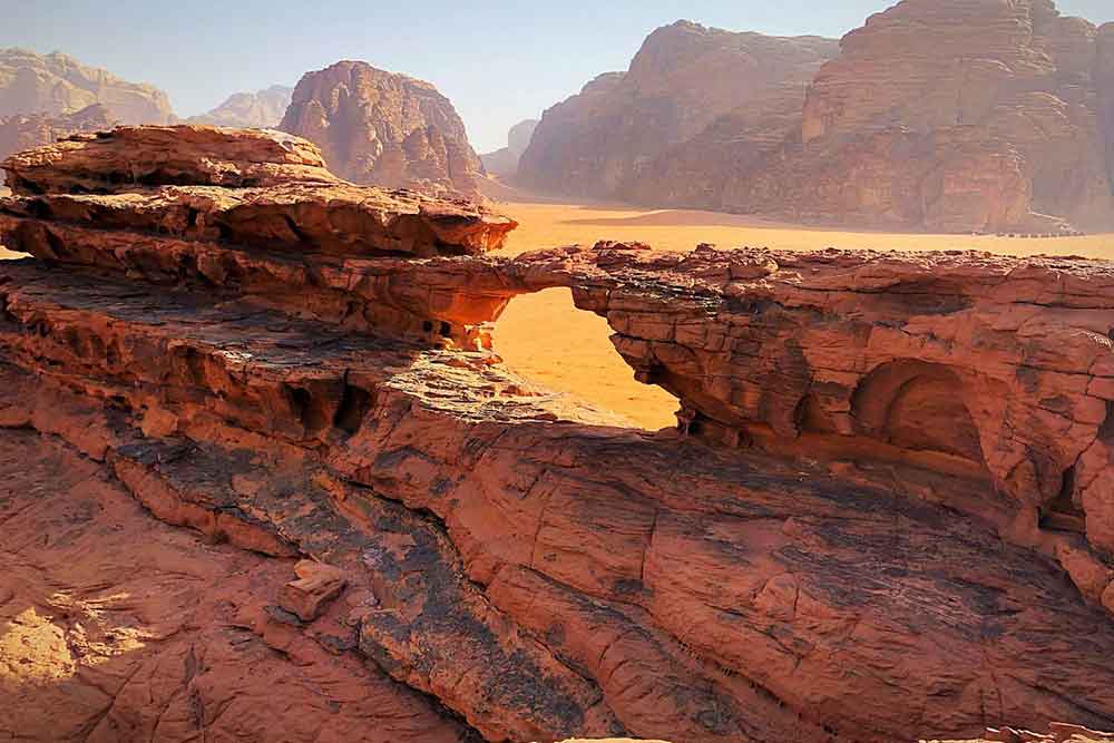 A red rock bridge formation in Wadi Rum. Visit is as part of this 10 days in Jordan itinerary. Includes Petra, Wadi Rum, Jerash, Amman, and more. The best Jordan 10 day itinerary for first time visitors.