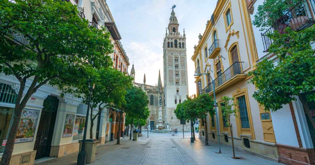 Image of the Giralda in Seville along a pedestrianised street, this is the featured image for an article about the best things to do in seville with 30+ things to add to your seville bucket list.
