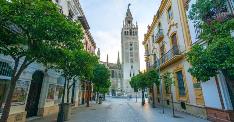 Image of the Giralda in Seville along a pedestrianised street, this is the featured image for an article about the best things to do in seville with 30+ things to add to your seville bucket list.