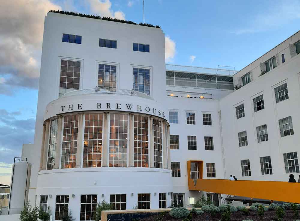 The brewhouse building showcases cream-white walls with multiple glass windows