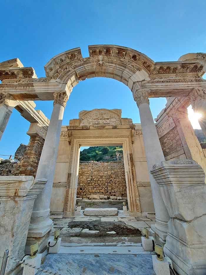 The temples at Ephesus feature gray-brown archways with intricate details on the top of the archways