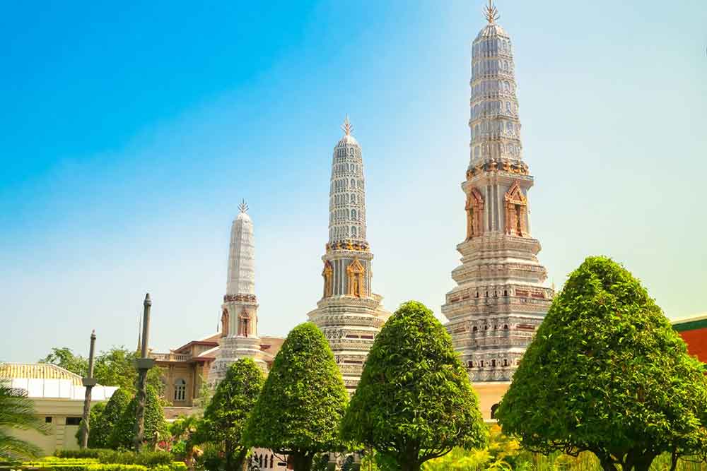 Is Bangkok Worth Visiting? 16 Great Reasons to Visit Bangkok 9 Lush green trees surround three towers in Thailand on a sunny day.