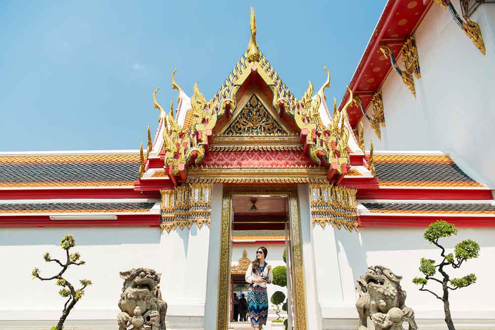 A woman in a dress is visiting the temple in Thailand