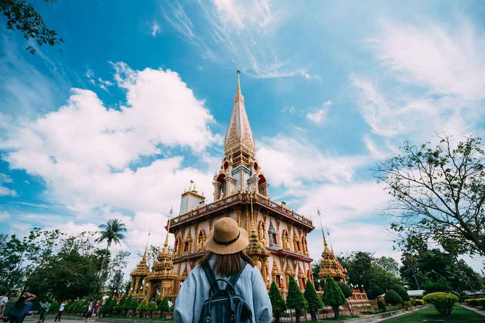 Does It Snow in Thailand? What to Expect in Thailand in Winter 4 Woman in a hat visit the Wat Chalong Phuket with a clear blue sky