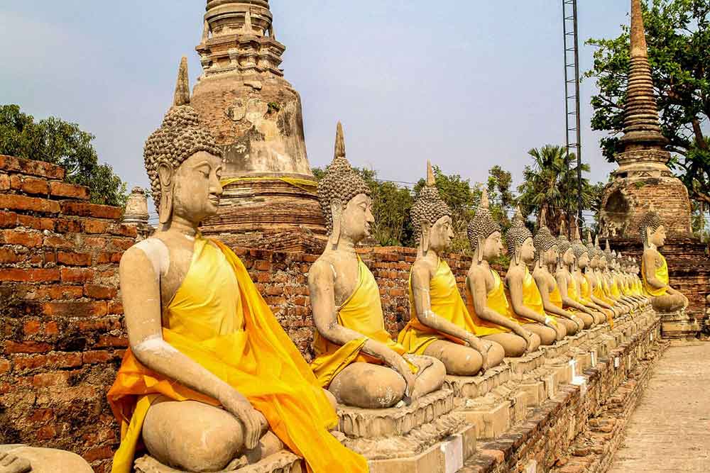 Does It Snow in Thailand? What to Expect in Thailand in Winter 1 Buddha statues in a row with orange robe at Ayutthaya Historical Park