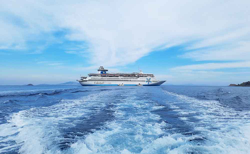 A cruise ship with blue sea and blue sky. There are clouds in the sky and waves in the sea. The Mediterranean makes a great option for a first-time cruise.