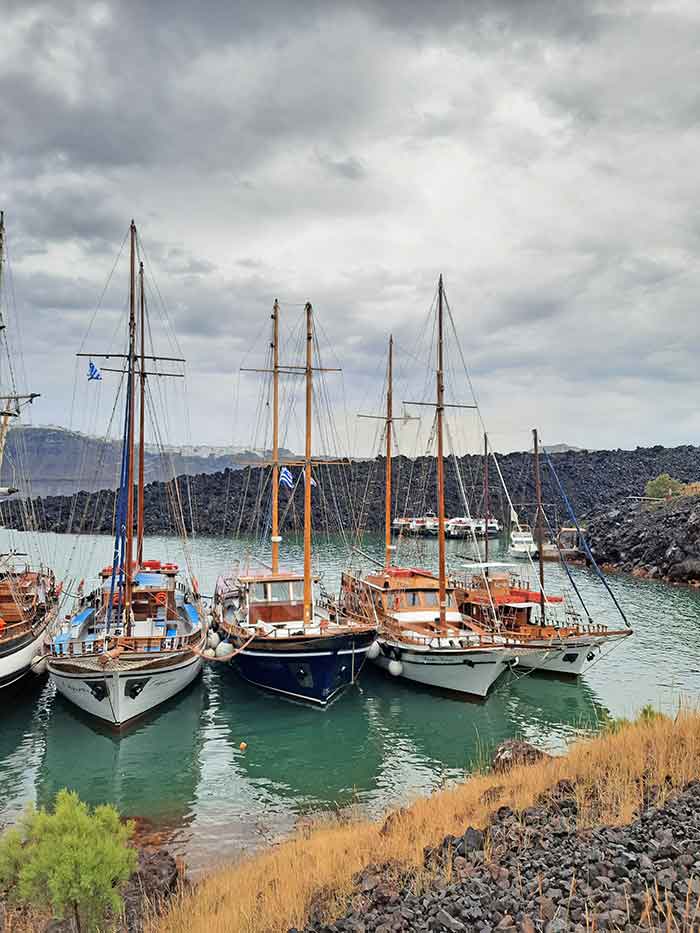 Fishing boats at Santorini Volcano Harbour in a cloudy sky