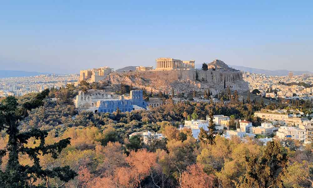 Philopappou Hill - panoramic views of the cityscape, pine trees and the acropolis during day time at athens