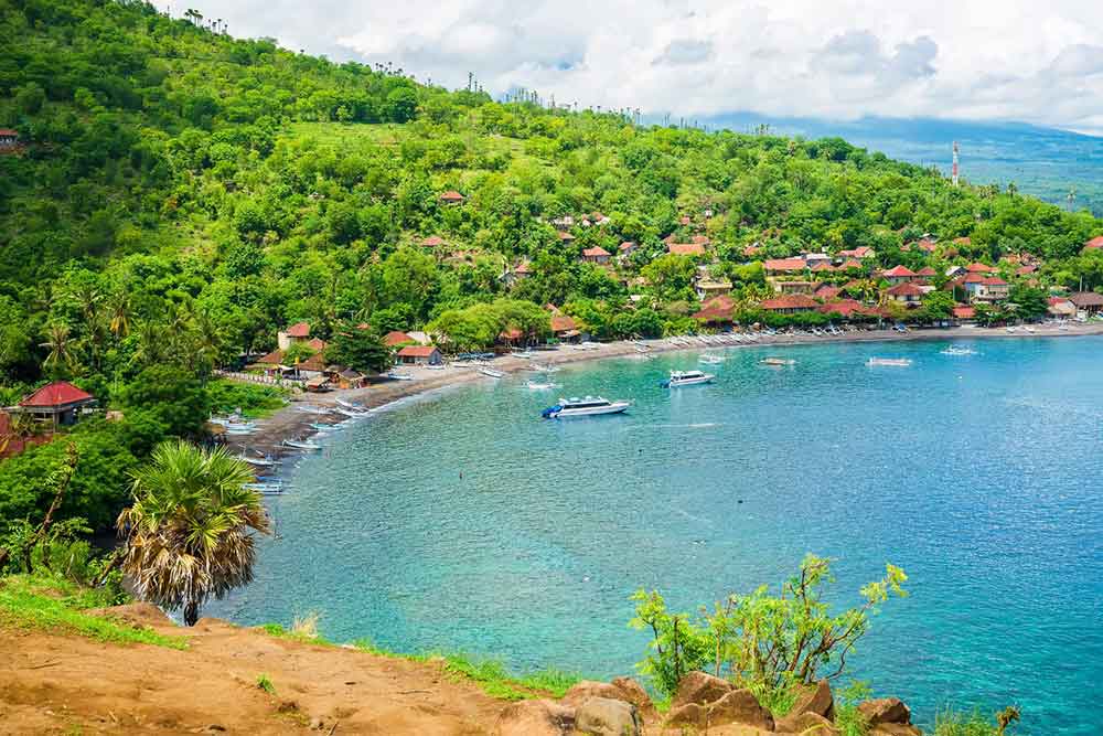 Amed Beach with boats in Bali surrounded by trees on the shore