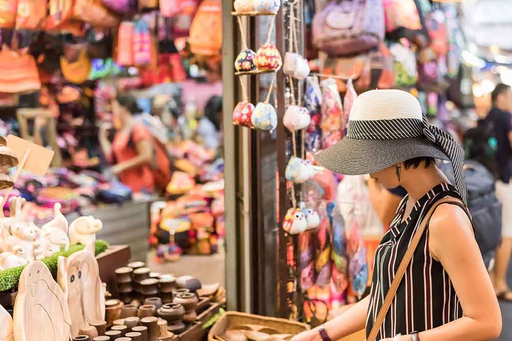 A woman with a hat is shopping for wood crafts at the Chatuchak Weekend Market