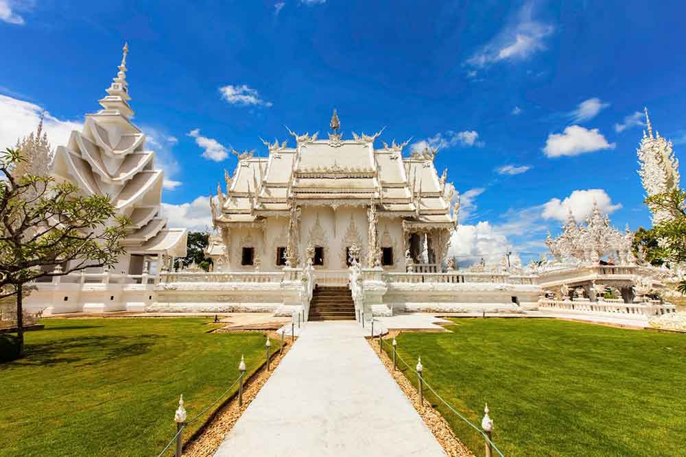 Wat Rong Khun, a fully white temple rising from the bottom up to the top in pristine white, is complemented by a lush green Bermuda grass in front of the temple