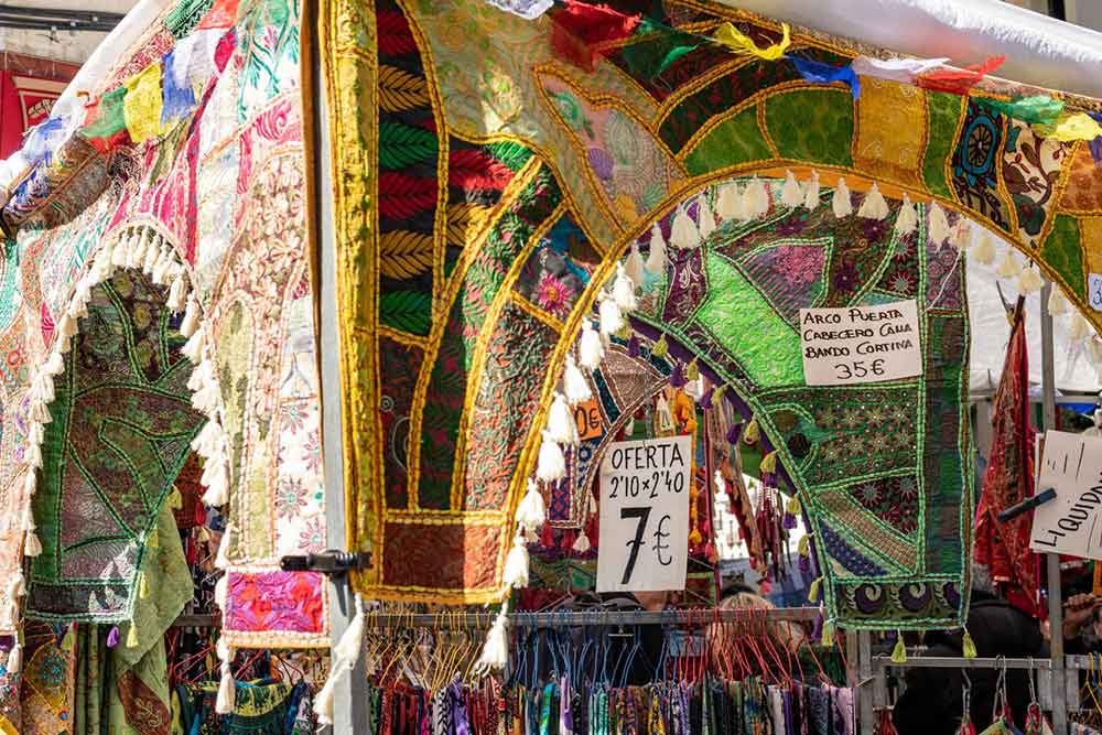 Colourful textiles hanging at El Rastro market, a lively stop for anyone exploring Madrid’s standout weekend experiences.