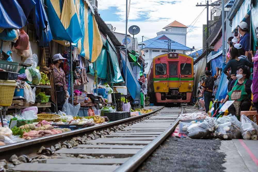Vendors swiftly set aside their goods in Maeklong Railway Market as the train approaches