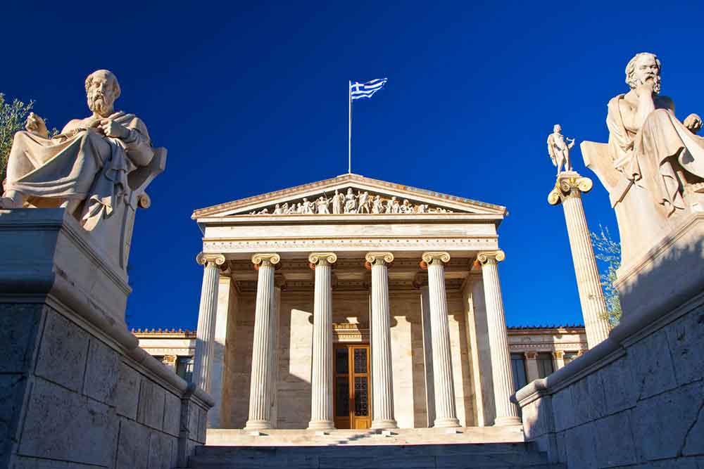 In front of the Plato's Academy, two statues sit under a clear blue sky