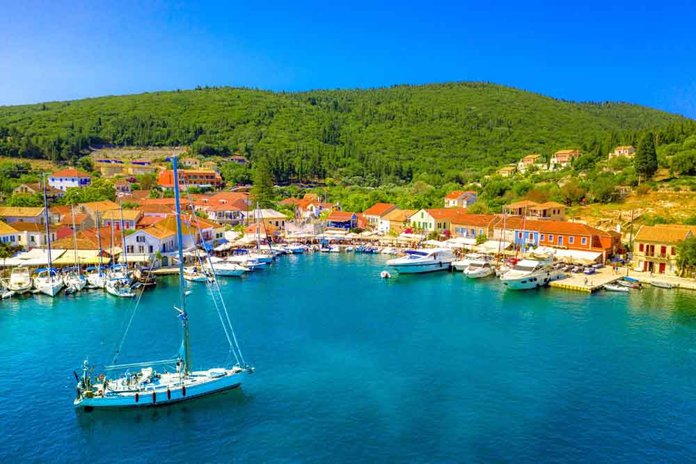 Clear water with a fishing boat and colorful houses in Fiscardo village in Kefalonia Island