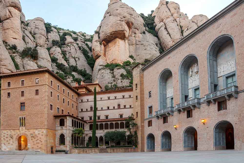 Barcelona Bucket List: 32 Best Things to Do in Barcelona, Spain 24 Unique rock formations with green trees located behind the building at Montserrat Barcelona
