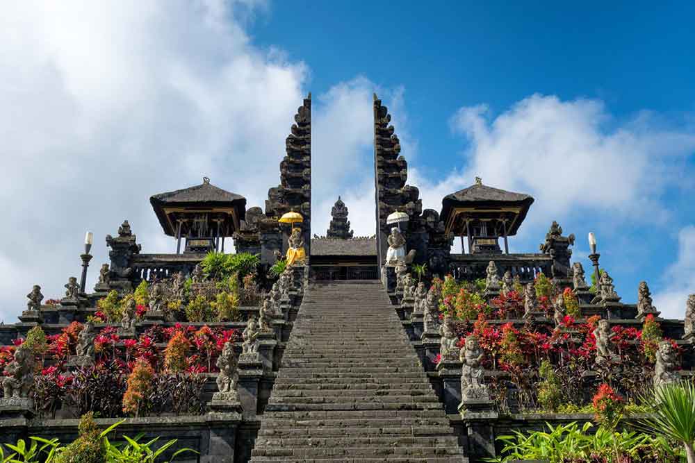 A stairway temple with statues and trees in a blue sky at Besakih Temple