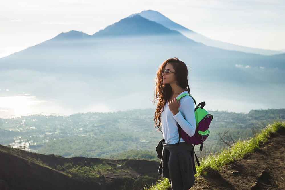 A woman with a backpack hike at Mount Batur catching the sunrise