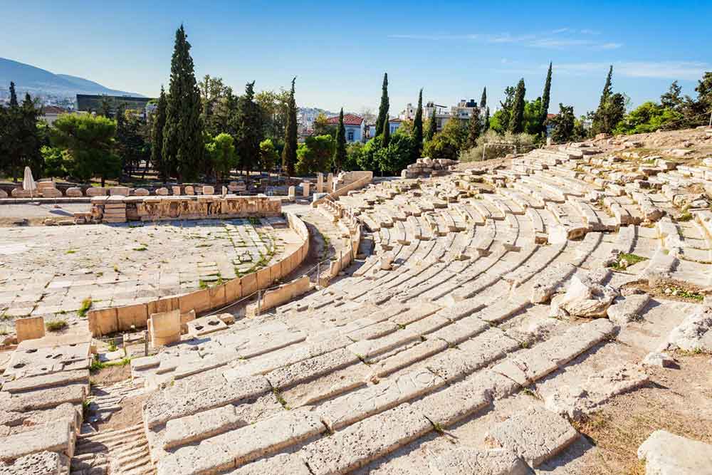 The Theatre of Dionysus features stone and marble benches arranged in a semi-circular shape, offering panoramic views of the landscape