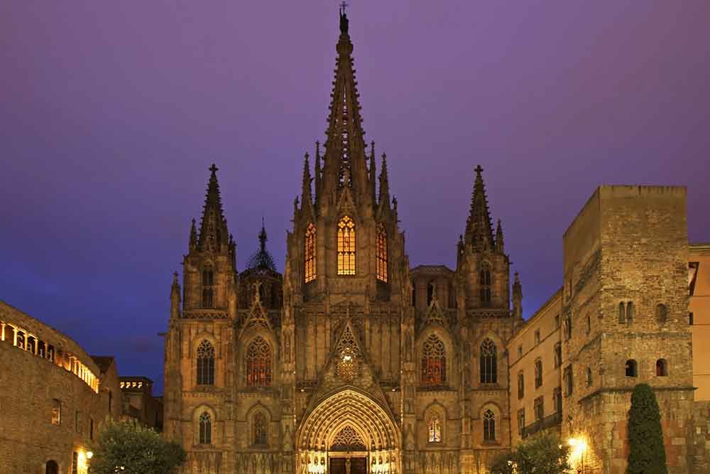 Gothic façade of the Barcelona Cathedral lit up at dusk, a prominent historic site in the heart of the city’s old town.