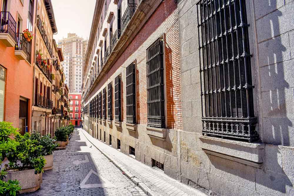 The vibrant streets of Madrid, adorned with peach and gray apartments, come alive on a perfect sunny day