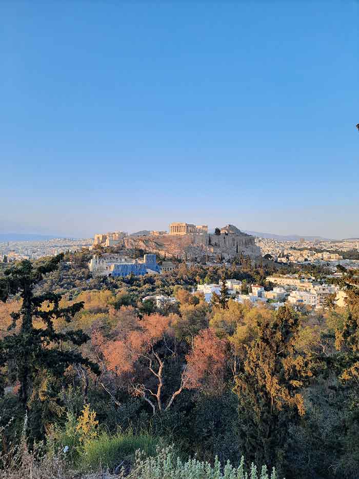From Philopappos Hill, you can see the breathtaking view of Athens, the surrounding trees, and the majestic temples