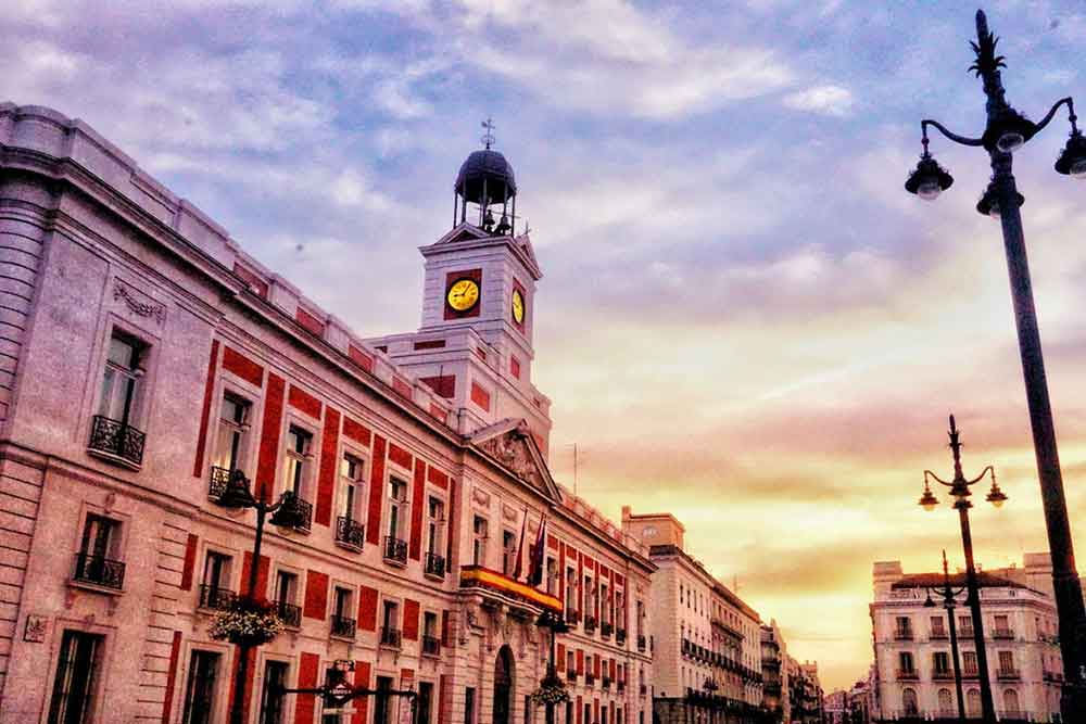 Sunset city skyline with the golden clock in a red-white washed building at Puerta del Sol, Madrid, Spain