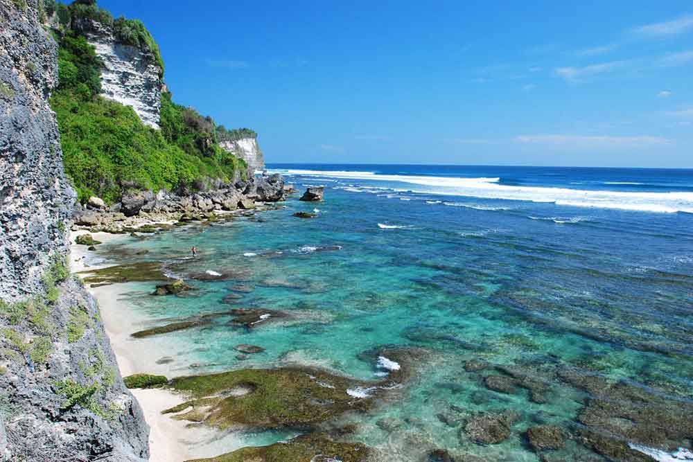 Blue sea in Uluwatu beach with cliff on the side