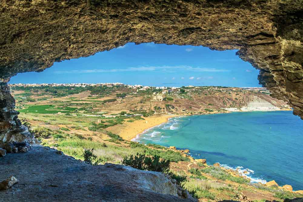 A view of the blue ocean, land and trees from Tal-Mixta cave
